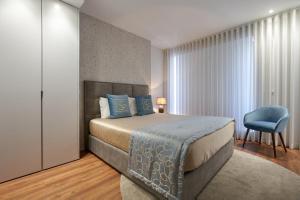 波尔图Signature Apartments Santa Catarina的一间卧室配有一张床和一张蓝色椅子