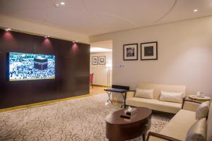 布赖代Al Aryam Serviced Aparthotel的客厅配有沙发和墙上的电视