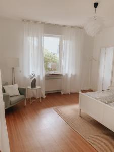 锡根Idyllische Stadtwohnung im Grünen的白色卧室设有床、椅子和窗户