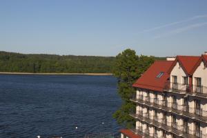 姆拉哥沃胡斯兹扎酒店的水体旁有红色屋顶的建筑
