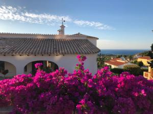 德尼亚Magic Dream Seaview Villa Denia with 2 Pools, BBQ, Airco, Wifi的前面有紫色花的房屋