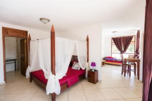 Los Duarte杜阿尔特角花园宾馆的一间卧室配有一张带天蓬的床