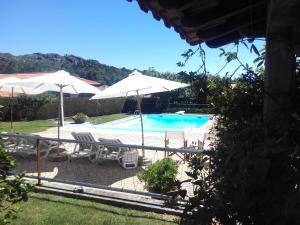 帕雷迪什迪科拉Casa Paz do Outeiro的一个带遮阳伞和椅子的游泳池以及一个游泳池