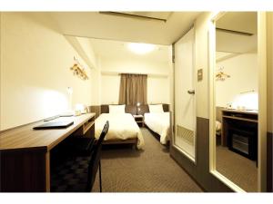 仙台Sendai Business Hotel Ekimae的酒店客房设有一间带书桌和床的卧室