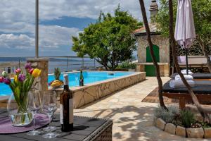 马卡尔斯卡Villa Sukara的游泳池旁的桌子,上面放着一瓶葡萄酒和鲜花