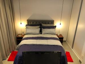 圣保罗Loft em Moema, próximo ao Metro, com estacionamento no condomínio的一间卧室配有一张带枕头的大床和电视。