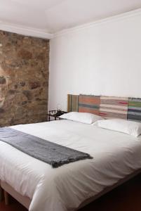 阿尔特杜尚Casa de Campo Alter Pedroso的卧室配有一张白色大床和石墙