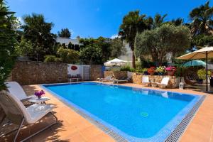 圣埃乌拉利亚Villa Blanca Santa Eulalia的庭院内的游泳池,配有椅子和遮阳伞