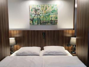 卢布尔雅那阿特里尔酒店的一间卧室配有一张带两个白色枕头的大床
