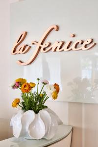 里米尼Hotel La Fenice的白色花瓶,桌子上摆放着鲜花,上面有标志