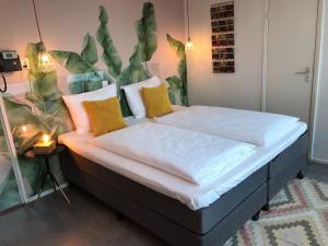 奈梅亨信诚酒店的一间卧室配有带白色床单和黄色枕头的床。