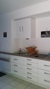 尚皮涅Le 10 Bis的厨房配有白色橱柜和水槽