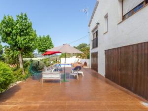 奥利维拉Welcoming Villa in Olivella with Swimming Pool的一座带椅子和遮阳伞的庭院位于大楼旁