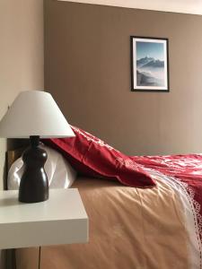 Condamine-ChâtelardLa Condaminoise的一张带红色毯子的床和一张带台灯的桌子