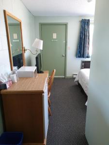 CochraneChimo Motel的客房设有一张桌子、一张床和镜子