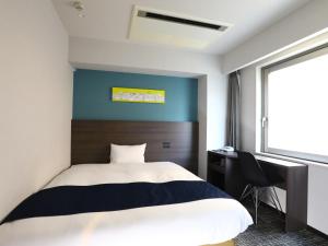 东京池袋永安国际酒店的一间卧室配有一张床、一张书桌和一个窗户。