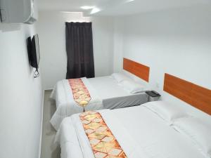 芙蓉Orange Villa Hotel Near Palm Mall Seremban的一间卧室配有两张床和电视。