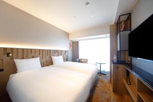 大阪Miyako City Osaka Hommachi的酒店客房设有两张床和一台平面电视。