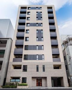 东京HIZ HOTEL Ginza的一座高高的公寓楼,设有许多窗户