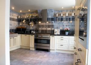 拉罗什-阿登Typical Ardenne House的厨房配有白色橱柜和炉灶烤箱。