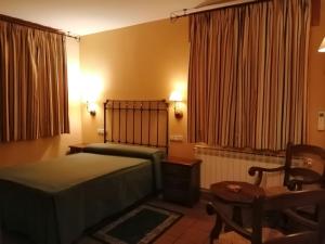 塞普尔韦达Hotel Rural & SPA Puente del Duratón的卧室配有1张床、1张桌子和1把椅子