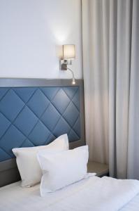 基辅Spa-Hotel Myslyvskiy Dvir的一张带蓝色床头板和白色枕头的床
