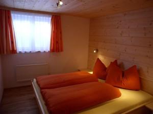 圣加伦基希Dreimäderlhaus的一间卧室配有带橙色枕头的床和窗户。