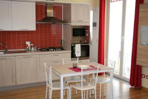 卡尔达诺阿尔坎波Le Margherite的厨房配有白色的桌椅和红色的瓷砖