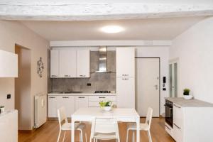 洛韦雷Feel at Home - NEL CUORE DI LOVERE的白色的厨房配有白色的桌子和椅子