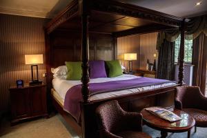 霍利Langshott Manor - Luxury Hotel Gatwick的一间卧室配有一张带两把椅子和一张桌子的天蓬床。