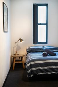 悉尼Wake Up! Bondi Beach的一间卧室配有一张床和一张带台灯的桌子