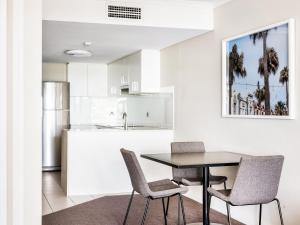 悉尼快斯特曼利酒店的厨房以及带桌椅的用餐室。