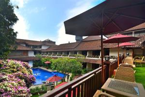 沙努尔阿里布德立酒店的一个带游泳池和遮阳伞的度假村阳台