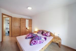 萨尔图西奥Strickerhof - Appartment 2的卧室配有一张带紫色枕头的大型白色床。