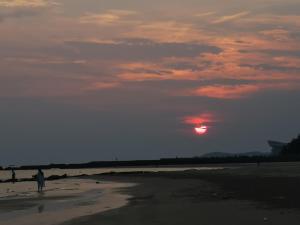 北海银泰时光海景别墅酒店的日落时站在海滩上的人