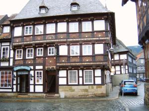 戈斯拉尔Altstadthotel Zur Börse的街道上的一座老建筑,前面有停车位