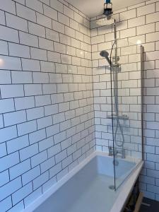 哈沃斯Withens Way Holiday Cottage, 2 Bedrooms, Haworth的白色瓷砖浴室设有浴缸和淋浴。