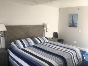 米德尔敦海滨瑞亚酒店的一间卧室配有一张带蓝白条纹毯子的床