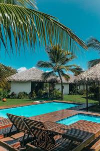 阿廷斯Atins Charme Chalés的一个带椅子和棕榈树的度假游泳池