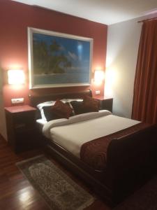 San Esteban de PraviaHotel Kerala的一间卧室配有一张床和两盏灯,墙上挂着一幅画