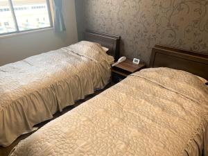 佐渡市Sado - Hotel - Vacation STAY 82496的一间卧室设有两张床,桌子上配有一部电话