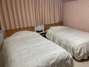 佐渡市Sado - Hotel - Vacation STAY 82476的配有窗帘和床衬的酒店客房内的两张床