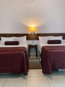 乌鲁阿潘HOTEL MI SOLAR EJECUTIVO的酒店客房,配有两张带红色床单的床