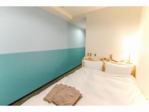 五岛SERENDIP HOTEL GOTO - Vacation STAY 82392的一间卧室配有一张带白色床单和蓝色墙壁的床。