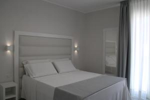 兰佩杜萨La Guitgia Rooms的白色的卧室设有白色的床和窗户。