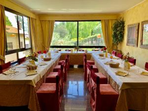 索里亚诺内尔奇米诺拉巴斯蒂亚度假酒店 的大型用餐室配有长桌子和红色椅子
