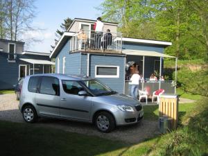 奥本罗Fjordlyst Camping & Cottages的停在房子前面的一辆小型银车