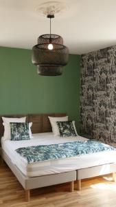 Saint-Sauveur-dʼAunisLa Rochelle et l'Aunis的一间卧室配有一张带绿色墙壁和吊灯的床。