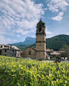 拉武埃尔达Apartamentos Turismo Rural Casa Alfós的一座古老的建筑,后面是一座带钟楼和山脉的建筑