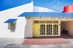 巴东OYO 3252 Lansano Residence Syariah的蓝色屋顶房屋的黄色门
